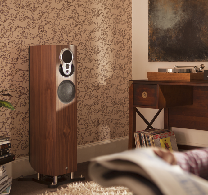Linn Akubarik Exakt Loudspeaker in a living room against a wall with a man sitting reading the paper