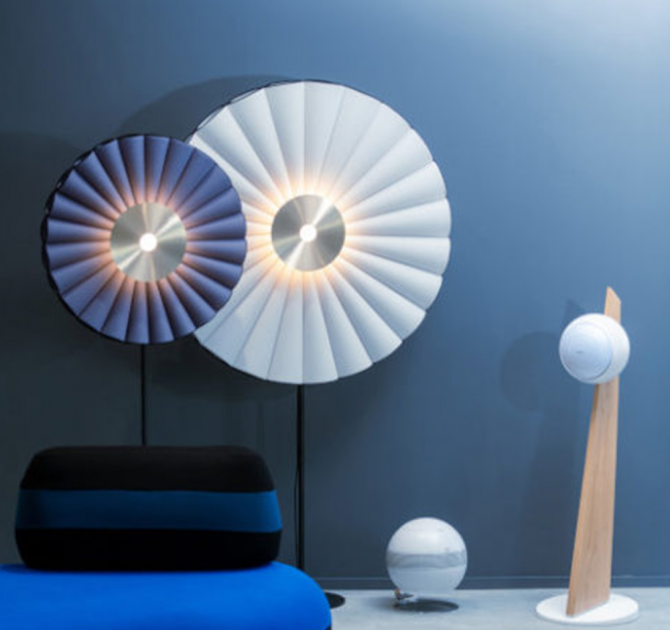 Cabasse Baltic 5 Sub System (on stand).  The sub is white.  The Baltic 5 speaker is white with a wooden stand.  There are two large circular lights, one white and one dark grey.  In the foreground there's a seat.