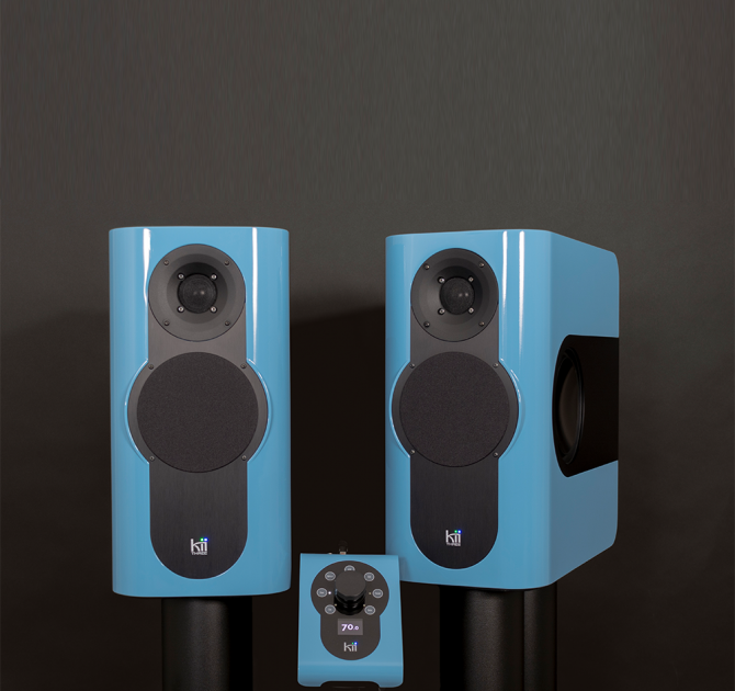 A pair of Kii Three Loudspeakers with the Kii Controller.  The speakers and the controller are a glossy blue colour
