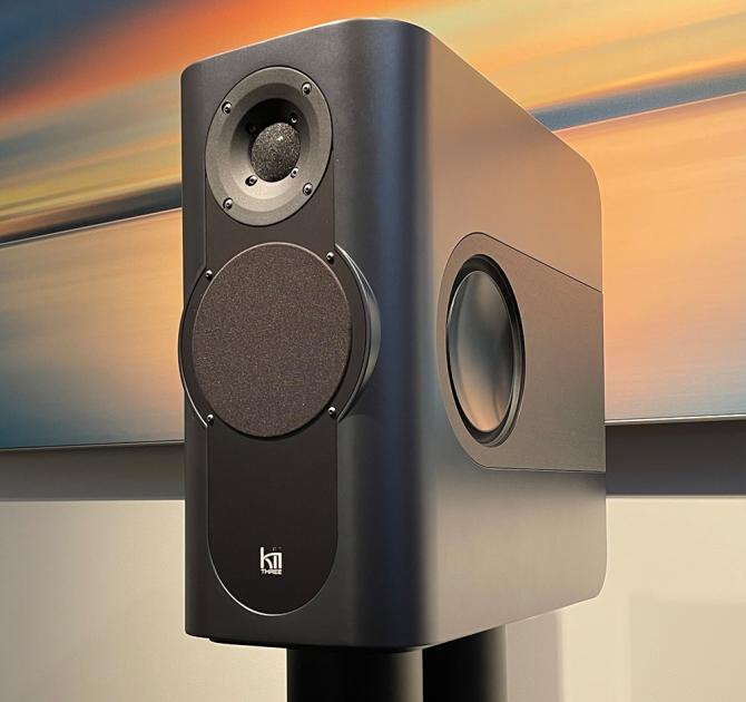 a grey rectangular speaker on a black stand with a piece of artwork in the background.