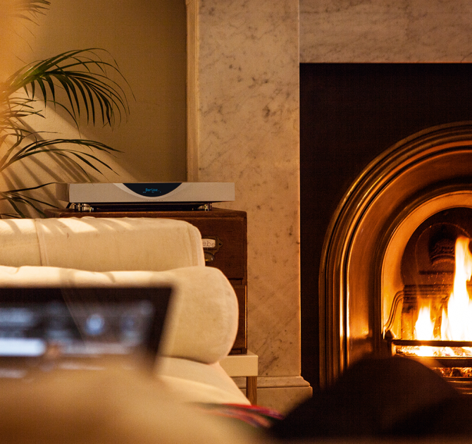 Linn Klimax DSM in silver next to a roaring living room fire.