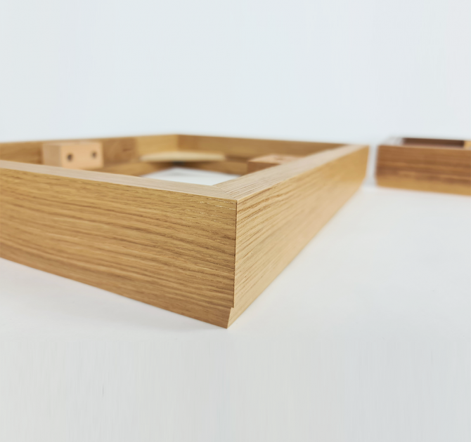 Close-up of the oak plinth with a corner of walnut visible in the background.