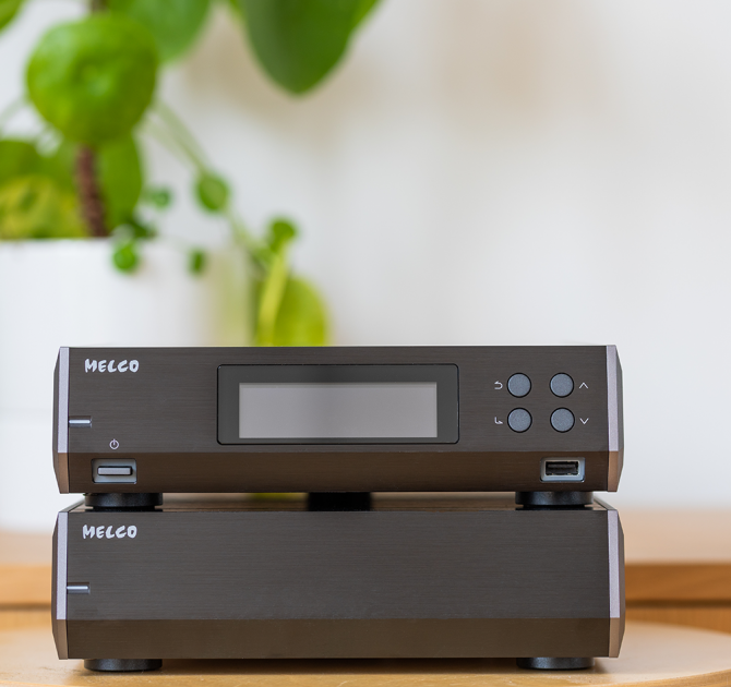 Melco N10/2 Digital Music Library in black, one on top of the other on a table with a plant in the background.
