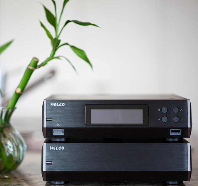 Melco N10/2 Digital Music Library in black, one on top of the other with a plant beside it on a table.