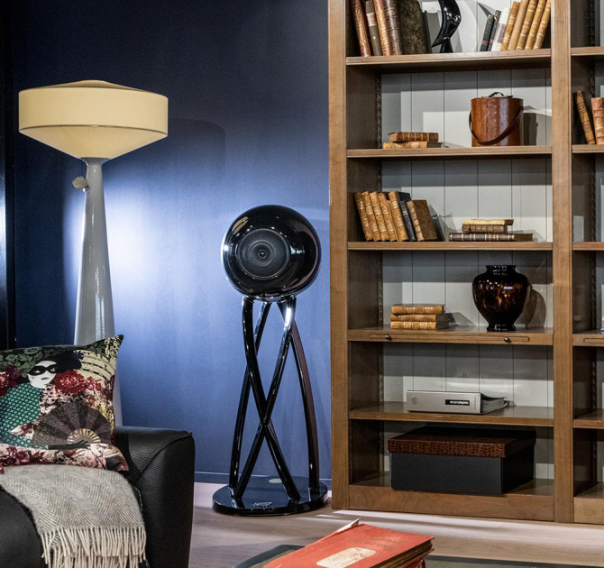 Cabasse Pearl Pelegrina Loudspeaker in black.  In a living room beside a book shelf