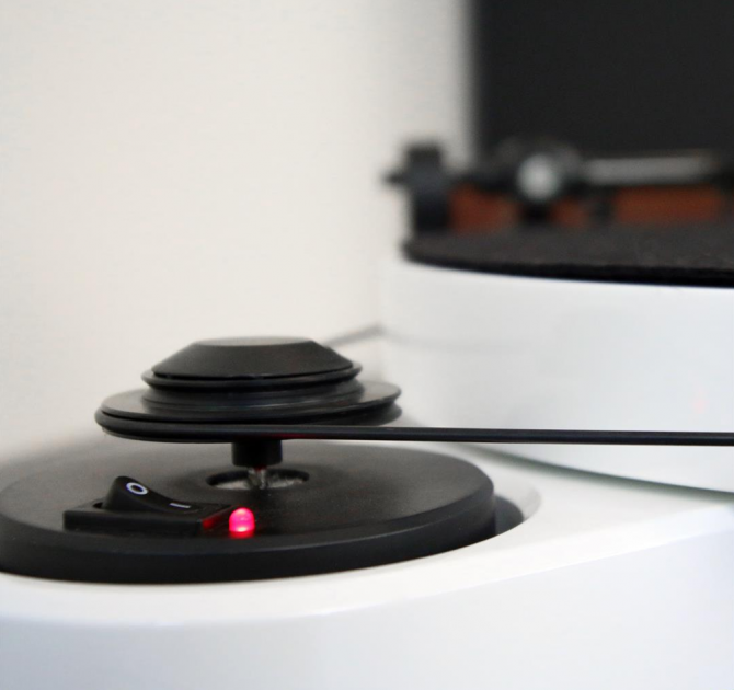 Project RPM 3 Carbon - Turntable in white.  Close-up side view of the on/off switch and the belt attachment.