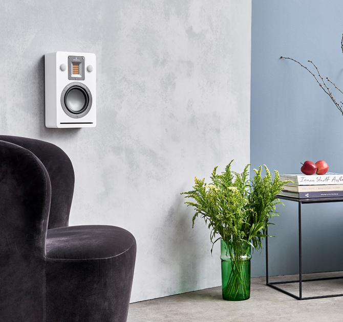 Audiovector QR Wall in white silk on a wall with a chair and table in view.