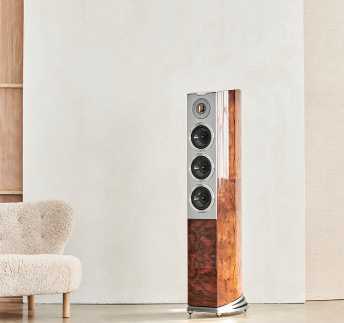 Audiovector R8 Arreté Loudspeaker in Italian Walnut Burl beside a cream sofa
