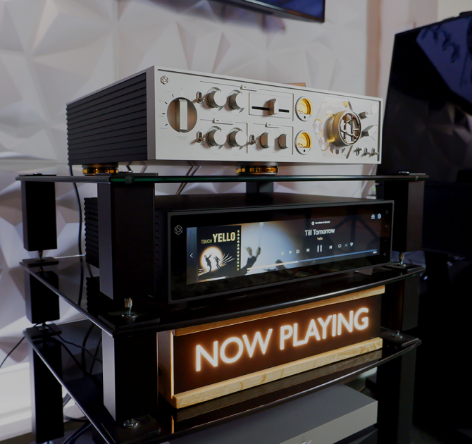 HiFi Rose RA180 on the top shelf of a HiFi stand.  Below is the rose RS150 streamer.  Below that is our 'Now Playing' sign.