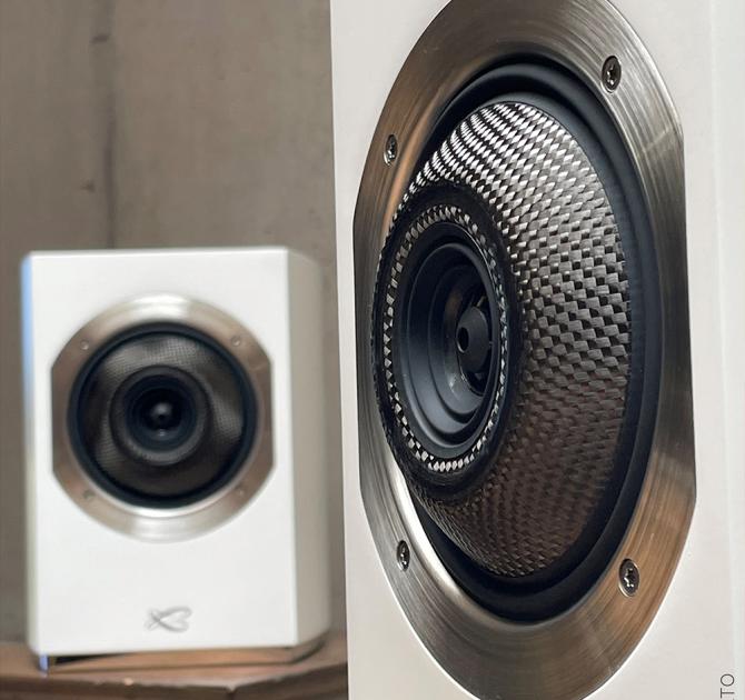 A pair of Cabasse Rialto Loudspeakers in white.  One up close and the other further away.