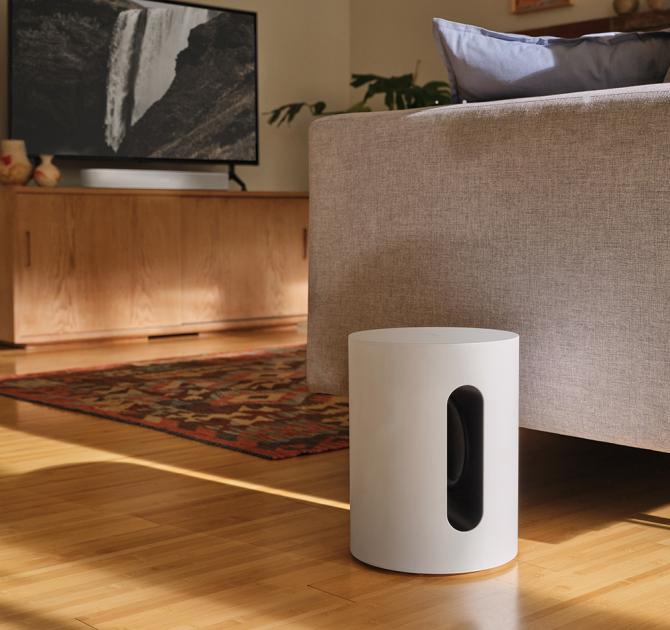 SONOS Sub Mini in white on the floor beside a sofa