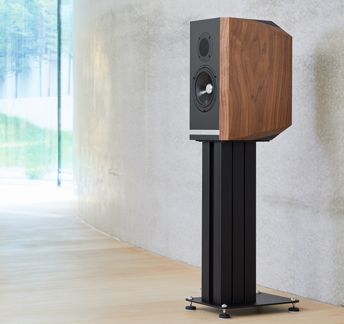 A single Titan 505 speaker on a stand with the grill off standing in front of a polished concrete wall.