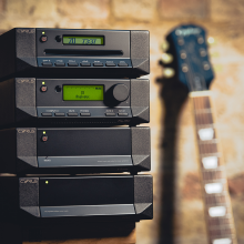 Cyrus CD T CD Transport stacked with other Cyrus products and a guitar leaning beside.