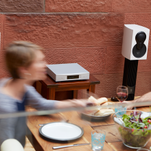 Linn Akurate DSM in silver on a table beside a dinner table.