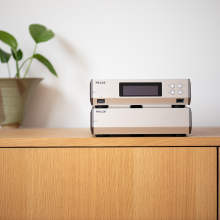 Melco N10/2 Digital Music Library in silver on top of a sideboard.  There's a plant in a pot beside it.
