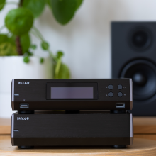 Melco N10/2 Digital Music Library in black on a wooden table with a speaker and plant in the background