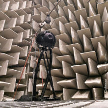 Cabasse Pearl Pelegrina Loudspeaker in black with a patterned wall behind.