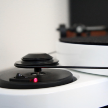 Project RPM 3 Carbon - Turntable in white.  Close-up side view of the on/off switch and the belt attachment.