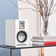 Audiovector QR1 on a table with books and a vase of flowers.