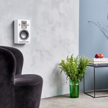Audiovector QR Wall in white silk on a wall with a chair and table in view.