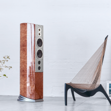 Audiovector R11 Arreté Loudspeaker in Madrona Burl in a white room beside an arty chair