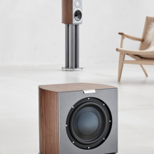 Audiovector R Sub in Italian Walnut with a chair and speaker in the background