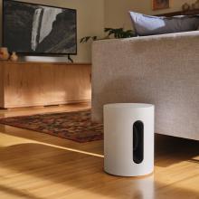 SONOS Sub Mini in white on the floor beside a sofa
