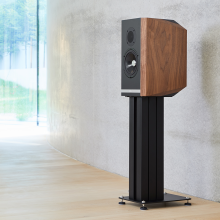 A single Titan 505 speaker on a stand with the grill off standing in front of a polished concrete wall.