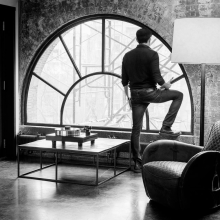 Project Xtension 10 (no cartridge) - Turntable on a low wooden table in front of a large semi-circular window with a man standing and looking out of the window.